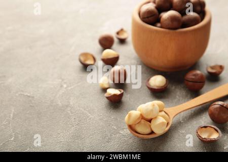Macadamia in wooden spoon on grey background. Favorite for snack and very delicious.Have a lot of unsaturated fatty acid. Healthy food concept. Top vi Stock Photo