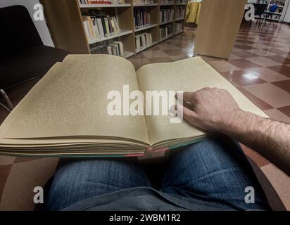 Blind male reading braille language book at library. Point of view shot Stock Photo