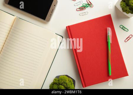 Red notebook with smartphone on grey background. Top view Stock Photo