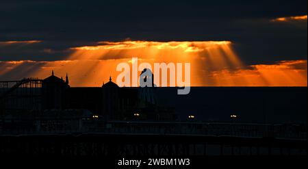 Brighton UK 11th January 2024 - The sun sets behind Brighton Palace Pier at dusk after another cold day along the South Coast with more snow forecast for early next week in the UK : Credit Simon Dack / Alamy Live News Stock Photo