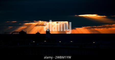 Brighton UK 11th January 2024 - The sun sets behind Brighton Palace Pier at dusk after another cold day along the South Coast with more snow forecast for early next week in the UK : Credit Simon Dack / Alamy Live News Stock Photo