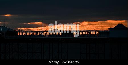 Brighton UK 11th January 2024 - The sun sets behind Brighton Palace Pier at dusk after another cold day along the South Coast with more snow forecast for early next week in the UK : Credit Simon Dack / Alamy Live News Stock Photo