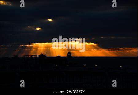 Brighton UK 11th January 2024 - The sun sets behind Brighton Palace Pier at dusk after another cold day along the South Coast with more snow forecast for early next week in the UK : Credit Simon Dack / Alamy Live News Stock Photo