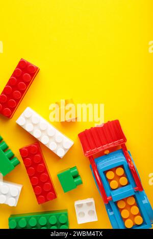 Multicolored blocks of the children's constructor lie on a yellow background. Stock Photo