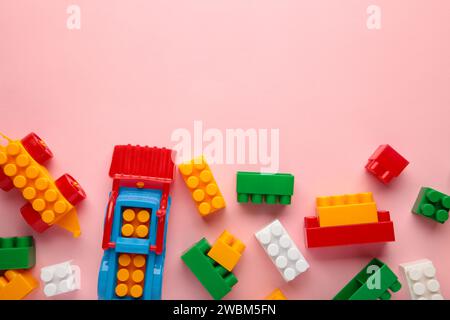 Multicolored blocks of the children's constructor lie on a pink background Stock Photo