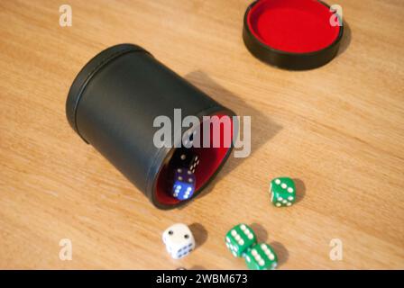 Dice spilling from black dice cup Stock Photo