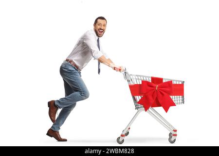 Full length profile shot of a young professional man running with an empty shopping cart tied with a red ribbon isolated on  white background Stock Photo