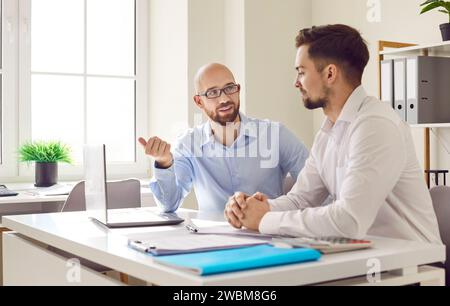 Two male business partners working with laptop together Stock Photo