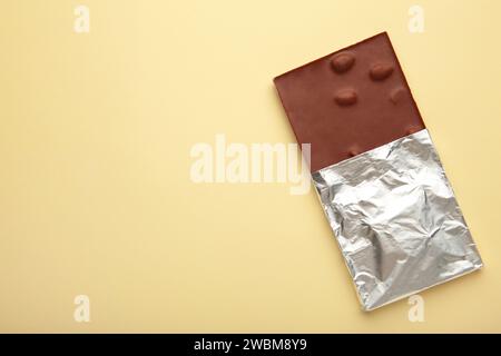 Chocolate wrapped in foil, clipping path on beige background. Top view Stock Photo