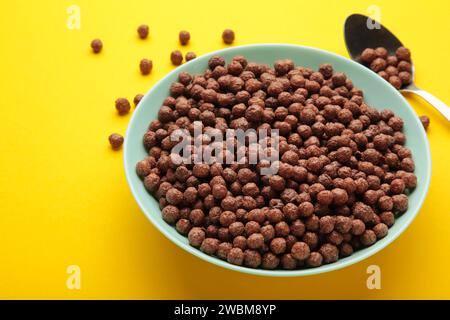 Chocolate corn balls in blue bowl on yellow background. Top view. Stock Photo