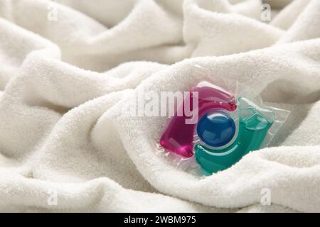 Washing gel capsule pods with laundry detergent on a pile of white cloth background. Stock Photo