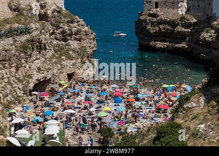 Italy, Puglia, Polignano a Mare: crowd of tourists on the Cala Porto beach during August Stock Photo