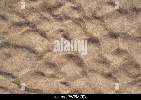 Fine brown sand with relief pattern on a beach in close-up Stock Photo