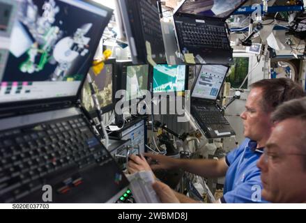 ISS020-E-037703 (1 Sept. 2009) --- Canadian Space Agency astronaut Robert Thirsk (right foreground, mostly out of frame), Expedition 20 flight engineer; and NASA astronaut Kevin Ford, STS-128 pilot, work controls of the station's robotic Canadarm2 in the Destiny laboratory of the International Space Station while Space Shuttle Discovery remains docked with the station. Stock Photo