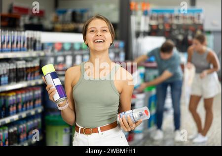 Young female customer buying spray paint can in supermarket Stock Photo