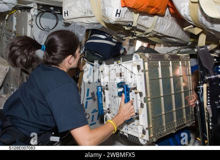 S128-E-007083 (31 Aug. 2009) --- Astronaut Nicole Stott, Expedition 20 flight engineer, prepares to move hardware through a hatch on the middeck of Space Shuttle Discovery (STS-128) while docked with the International Space Station. Stock Photo