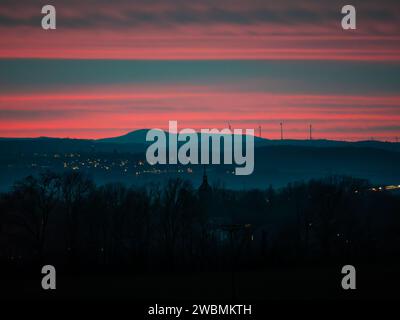 Sunset sky during nightly twilight in a mountain landscape. The clouds are illuminated in red color. Nature in the Saxon Switzerland. Stock Photo