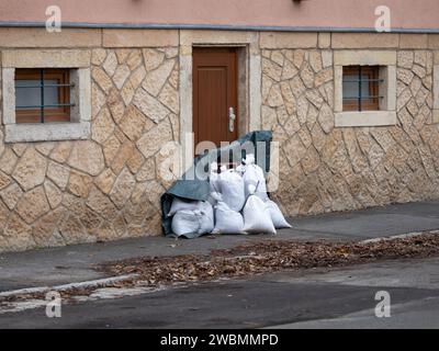 Sandbags as flood prevention in front of a door of a house. The owner of the building is protecting his property against water from an extreme weather Stock Photo