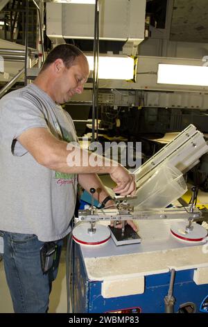 CAPE CANAVERAL, Fla. -- A United Space Alliance technician examines one of shuttle Atlantis' thermal protection tiles in Orbiter Processing Facility-1 at NASA's Kennedy Space Center in Florida. The tile went through a pull test, which measured the force it took to pull it off of the shuttle in order to make sure the bond between the two is strong enough to withstand the force of launch and landing. Atlantis is being prepared for the STS-135 mission, which will deliver the Raffaello multipurpose logistics module packed with supplies, logistics and spare parts to the International Space Station. Stock Photo