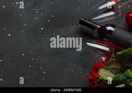 Bottle of wine with glasses and red roses on black background. Valentine's Day celebration Stock Photo