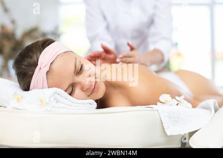 Young woman relaxing in spa center during back and shoulders massage Stock Photo