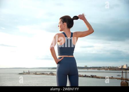 Rear view of a sporty woman holding her ponytail, preparation before exercise. Stock Photo