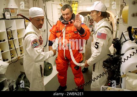 KENNEDY SPACE CENTER, Fla. - Expedition Three crew member Vladimir Dezhurov waves as he is helped with his launch and entry suit before he enters Space Shuttle Discovery for launch. Helping him are (left) NASA Astronaut Support Personnel John Herrington and (right) USA Mechanical Technician Al Schmidt. The payload on the STS-105 mission to the International Space Station includes the third flight of the Italian-built Multi-Purpose Logistics Module Leonardo, delivering additional scientific racks, equipment and supplies for the Space Station, and the Early Ammonia Servicer (EAS) tank. The EAS, Stock Photo