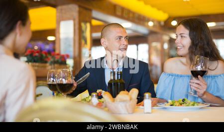 Two cheerful couples having dinner and nice talking Stock Photo