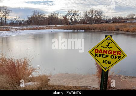 Denver, Colorado - A sign warns of thin ice on a pond along the Clear Creek Trail. The hiking/biking trail runs 19 miles from Golden, Colorado to the Stock Photo