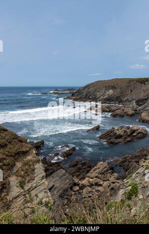 serene yet dynamic natural beauty of a rocky coastline with waves crashing under a clear sky Stock Photo
