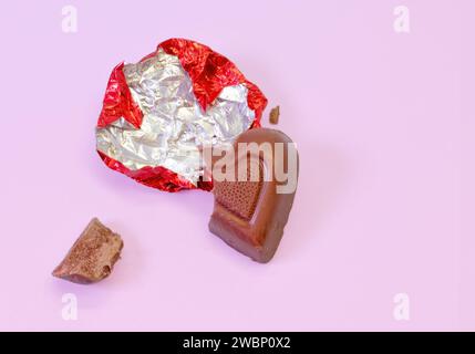 A Piece of Foil Covered Valentine's Day Milk Chocolate Candy on a Bright Pink Background Stock Photo