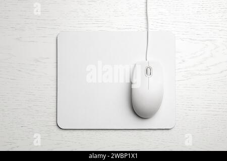 Wired computer mouse and pad on white wooden background, flat lay. Space for text Stock Photo