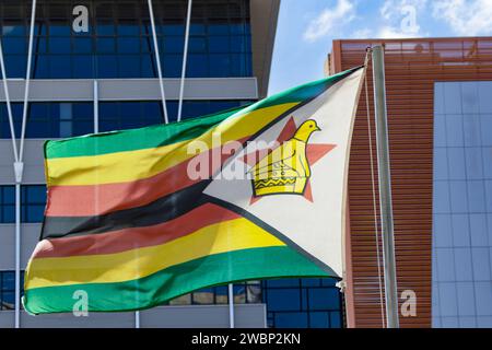 zimbabwe flag on the pole, blue sky with clouds Stock Photo
