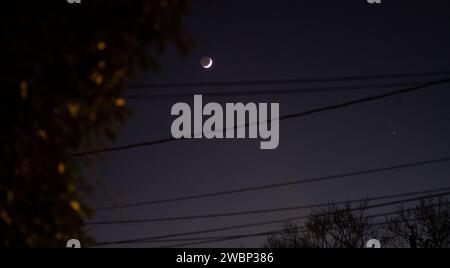 The Moon, left, Saturn, upper right, and Jupiter, lower right, are seen after sunset from Alexandria, Va., Thursday, Dec. 17, 2020. The two planets are drawing closer to each other in the sky as they head towards a “great conjunction” on December 21, where the two giant planets will appear a tenth of a degree apart. Stock Photo