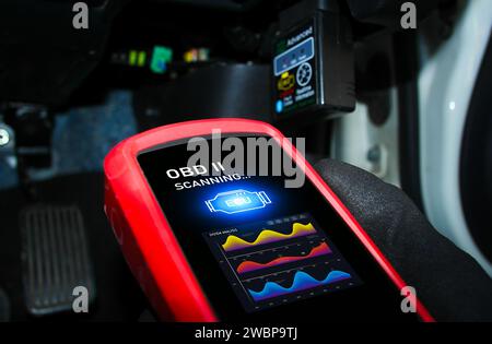Auto mechanic checking ECU engine system with OBD2 wireless scanning tool and car information showing on screen interface , Car maintenance service co Stock Photo