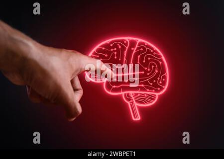 Hand and glowing brain shaped circuit board on black background. Artificial intelligence concept. Stock Photo