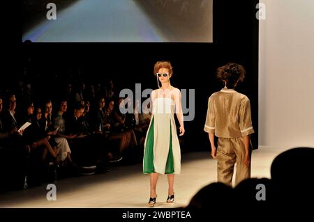 Two fashion models pass on the runway as rows of people in the audience  look on - CHADDI by Chad Nguyen at Raffles International Showcase Stock Photo