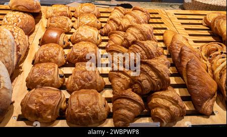 Variety of breakfast pastries pain au chocolat and french chocolatine croissant on wooden table display in bakery shop Stock Photo