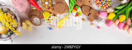 Family preparation for Easter. Holiday baking background, woman and child hands decorate homemade cookies with sugar glaze, in form of Easter symbols Stock Photo