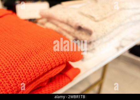 selective focus, red white wool sweaters folded on a clothing store rack Stock Photo