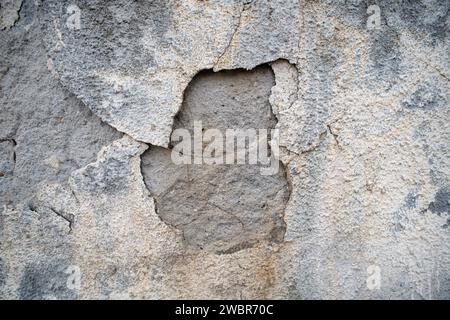 Cracked, peeled and damaged exterior wall plaster, gray, no people. Stock Photo