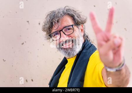senior man smiling doing victory sign with hand Stock Photo