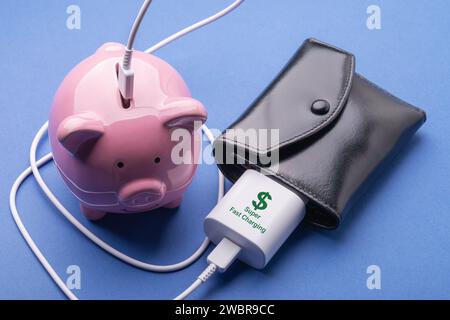 Piggy bank, wallet and smartphone charger on a blue background, concept on the theme of making money Stock Photo