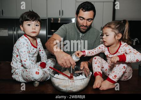 Dad and kids mix dough joyfully Stock Photo