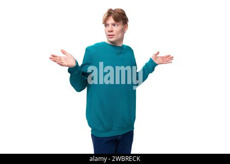 portrait of a confused slender young european man with red hair in a blue sweater Stock Photo