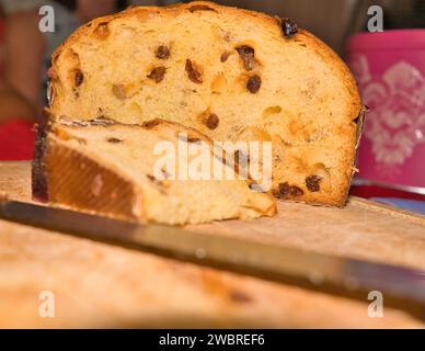 Panettone on chopping board, one cut slice and a cake knife during festive seasons Stock Photo