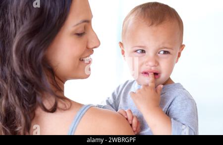 Mom holding crying baby boy in home with comfort, bonding and child care in morning. Happy woman, sad toddler and security together in bedroom with Stock Photo