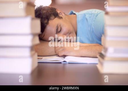 University books, education and tired man sleeping during academy study, research or knowledge learning. College, textbook and Indian student with Stock Photo