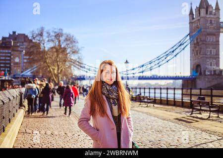 Young woman standing in front of Tower Bridge, London, UK Stock Photo