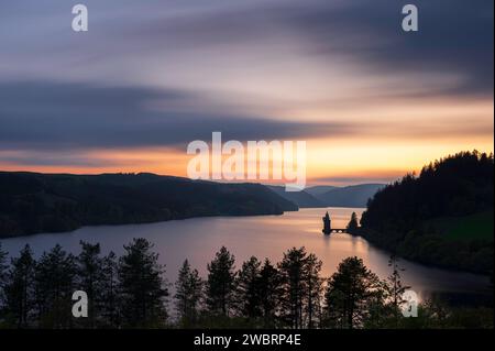 Lake Vyrnwy, located in mid Wales, an area of outstanding natural beauty, at sunset. The orange sky is reflected in the calm water of the lake Stock Photo